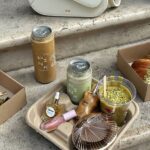 Signature To-Go Brunch Set – Budapest | Pink Pistachio Brunch Signature to-go brunch items at Pink Pistachio Brunch in Budapest, featuring canned iced drinks, pistachio desserts and pastries packed for takeaway