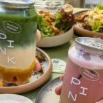 Signature To-Go Drinks Brunch Table – Budapest | Pink Pistachio Brunch Signature iced drinks served in cans at Pink Pistachio Brunch in Budapest, held above a pistachio-driven brunch table